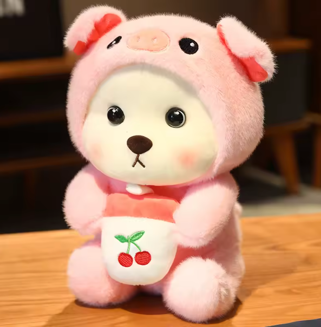 plush bear dressed in a pink pig outfit with a cherry-embroidered bib